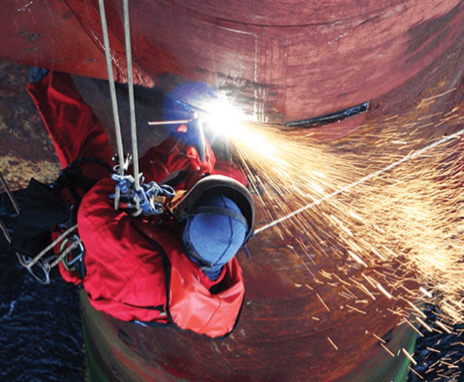 Worker welding on suspended structure.