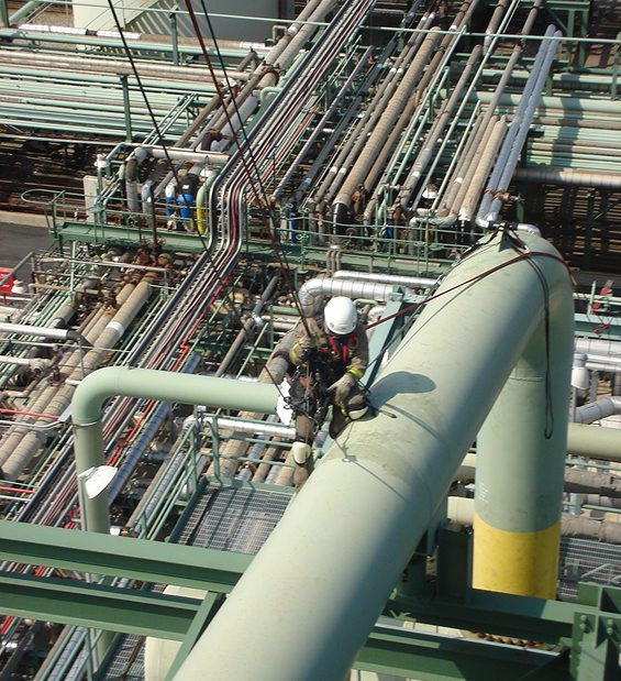 Worker inspecting industrial pipes and equipment.
